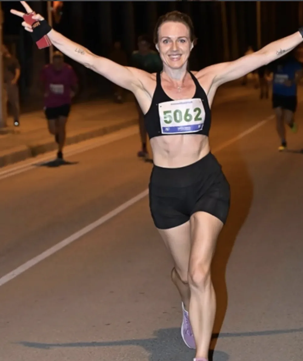 Ana finishing a marathon, arms raised