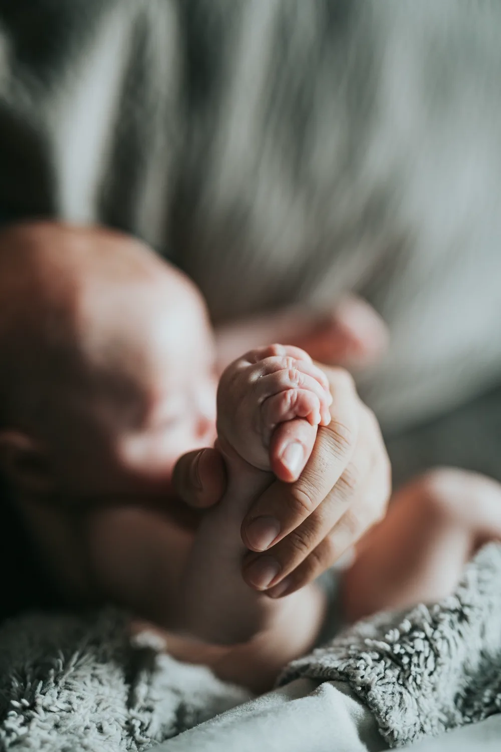 A parent holding a newborn's hand